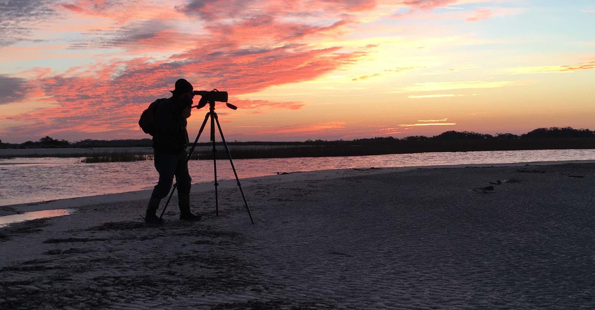 Man with camera at sunset on beach
